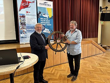 Daniel Kirchmeier (links) bekommt als frisch gewählter Commodore des YCA das Steuerrad vom scheidenden Commodore Gottfried Rieser überreicht.