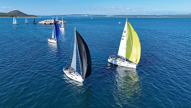 Mehrere Segelschiffe auf Raumschot Kurs bei sehr moderatem Wind, im Hintergrund der Gnalic, eine kleine Felsinsel nahe Biograd. Ganz rechts mit gelbem Genaker das Siegerschiff, die BellaVita.